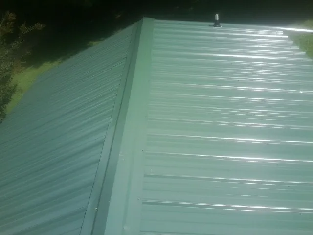 New green metal panels meeting at the ridge of a roof — Flat Roof Repair work by our crew in Pendergrass