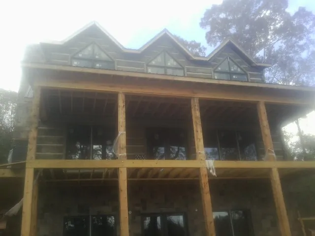 Dormers and porch framing on a large log home under construction — Roof Coating work by our crew in Pendergrass