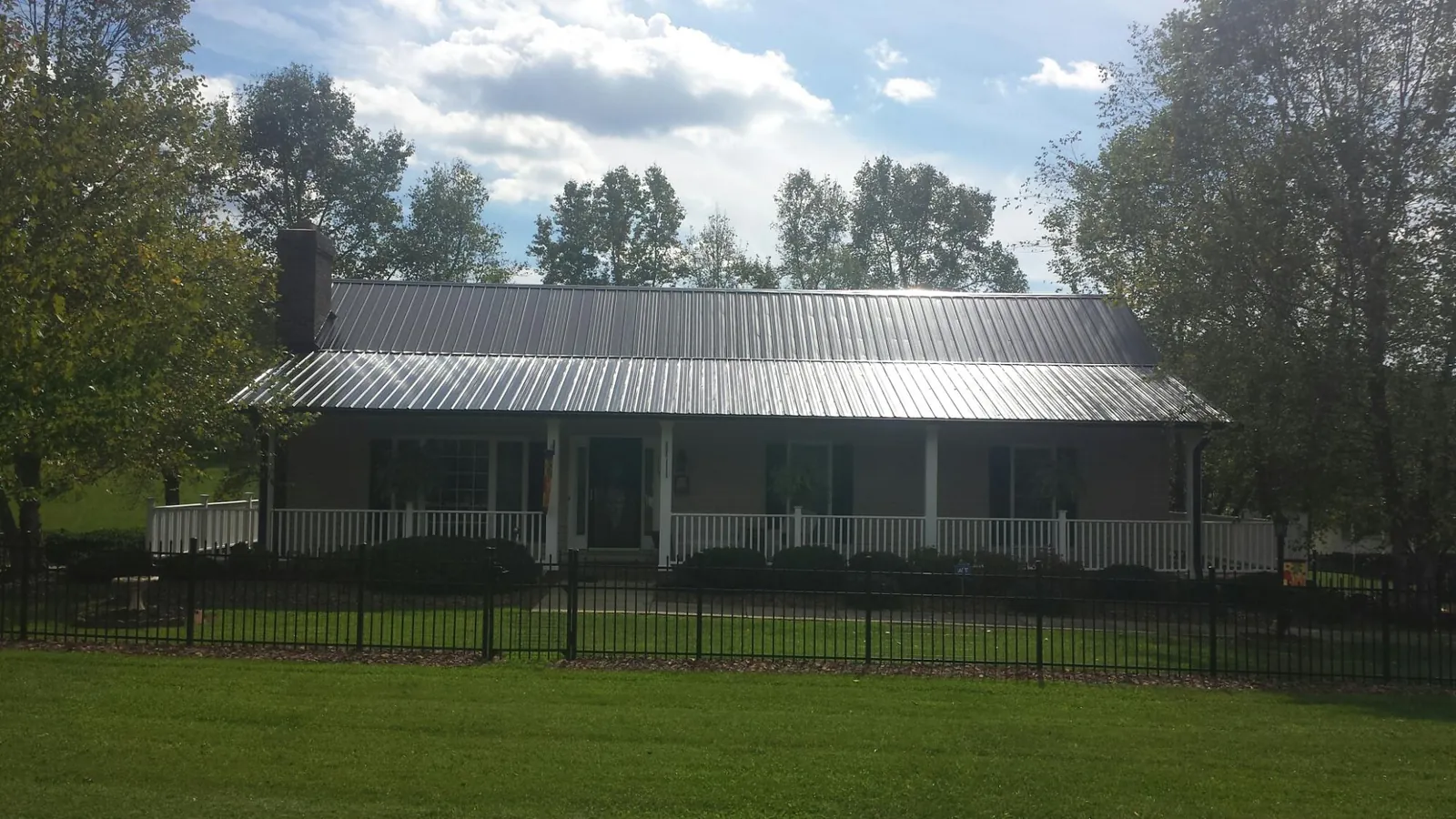 Gray metal roof on a brick ranch with a full width front porch — Gutter Guard Installation work by our crew in Pendergrass